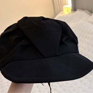 Black newsboy hat with adjustable strap.